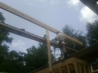 Carpenter setting a ridge beam over a new addition frame — Ice Dam Removal by Roofing Brothers in Altmar