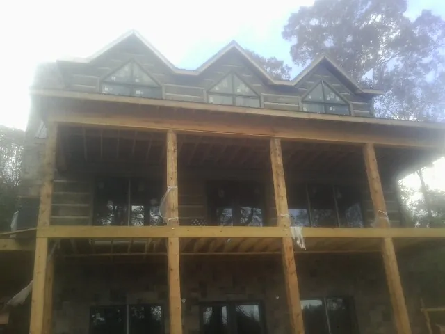 Dormers and porch framing on a large log home under construction — Roof Coating work by our crew in Altmar