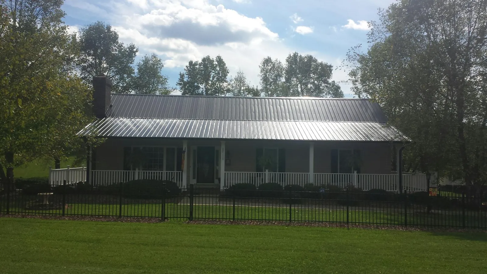 Gray metal roof on a brick ranch with a full width front porch — Gutter Guard Installation work by our crew in Altmar
