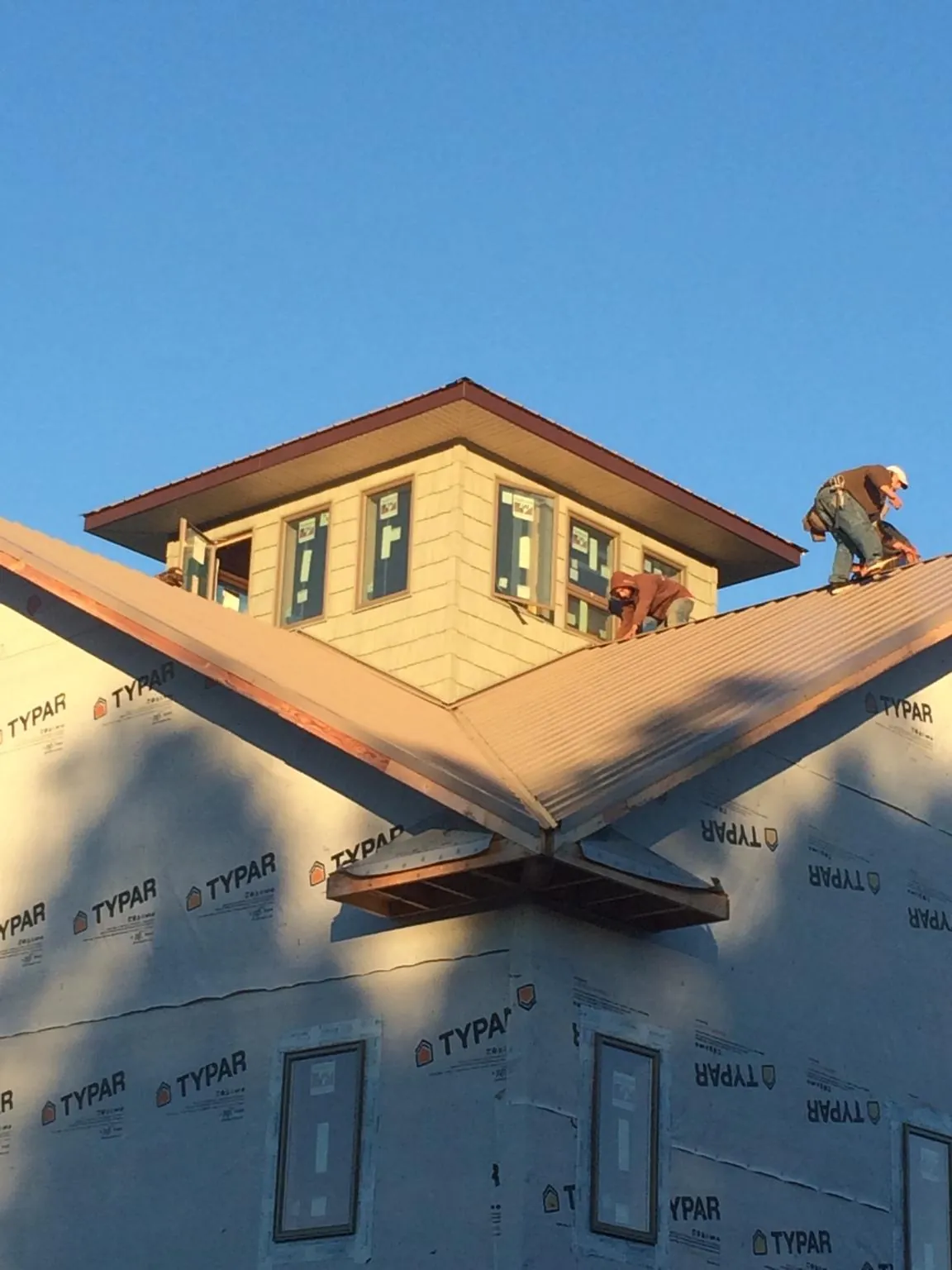 Roofers working around a rooftop cupola on a new metal roof at sunset — Roof Waterproofing in Altmar by Roofing Brothers